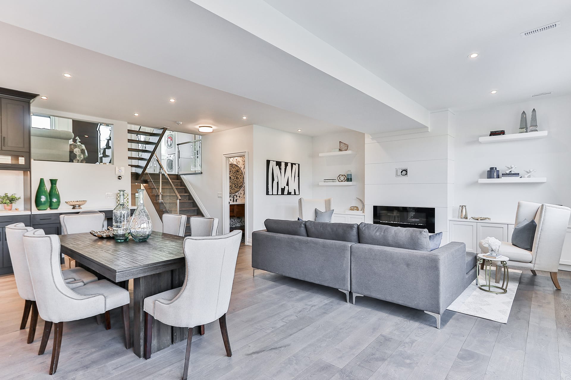 Modern living room corner with dark wood dining table and corner sofa, showing where a corner wine cabinet fits